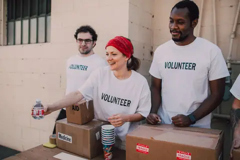 Smiling campaign-style volunteers in matching shirts greeting people at an outdoor table